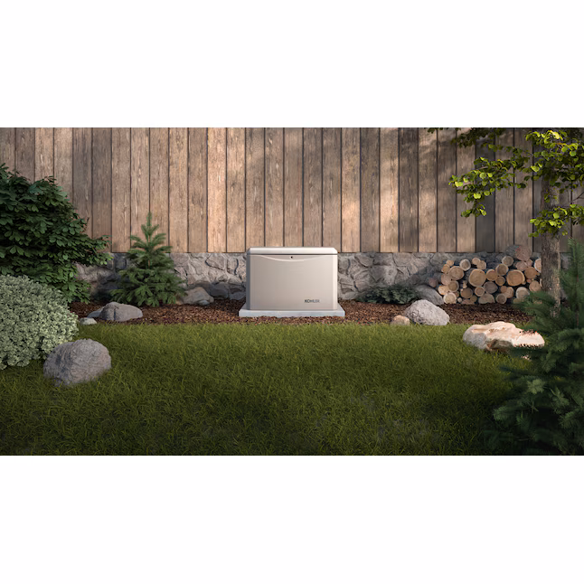 Kohler RCAL 14,000 Watt Dual Fuel Home Standby Generator installed in a landscaped yard with greenery and wooden fence.